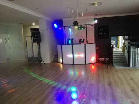 Stanowisko DJ Master z kolumnami i oświetleniem na sali z drewnianą podłogą