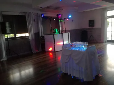 Stanowisko DJ Master w przyciemnionej sali, na pierwszym planie stół z kieliszkami podświetlonymi na niebiesko