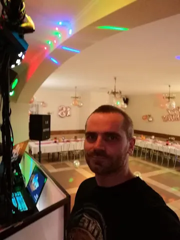 Bogumił Rydelski przy konsoli, w tle sala udekorowana na osiemnastkę